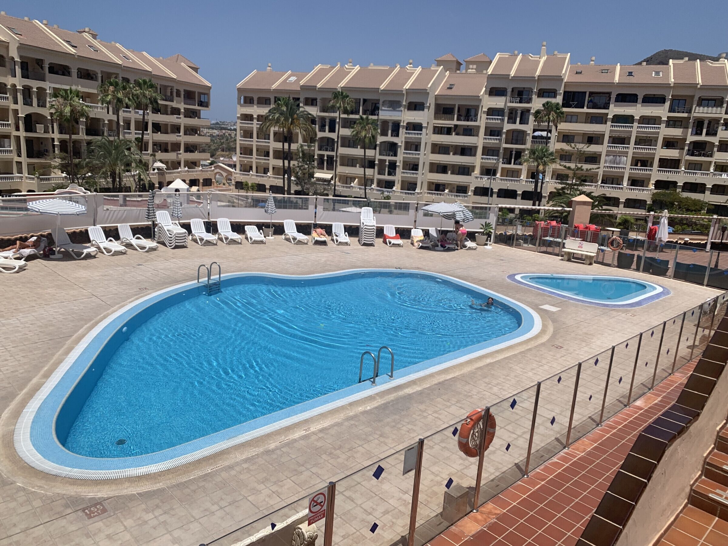 A hotel pool area with multiple pools, sun loungers, and a lifebuoy.