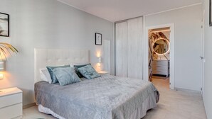 Une chambre moderne avec un grand lit, des tables de chevet, un tapis moelleux et un dressing.