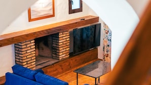 A cozy living room with a fireplace, a television, and blue furniture.
