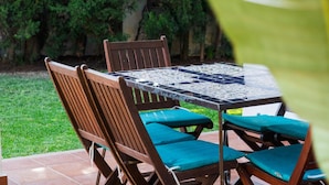 An outdoor patio with a tiled table and wooden chairs with teal cushions.