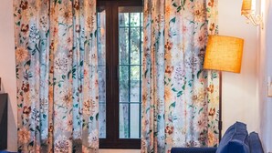 A room with a blue sofa, a small table, and curtains with a floral pattern.