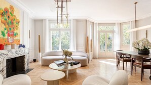 Un salon spacieux avec une cheminée, un canapé, une table basse et un coin repas comprenant une table et des chaises.