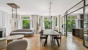 Un vaste espace dédié à la salle à manger, avec une longue table et des chaises, le tout entouré de grandes fenêtres offrant une vue sur la verdure.