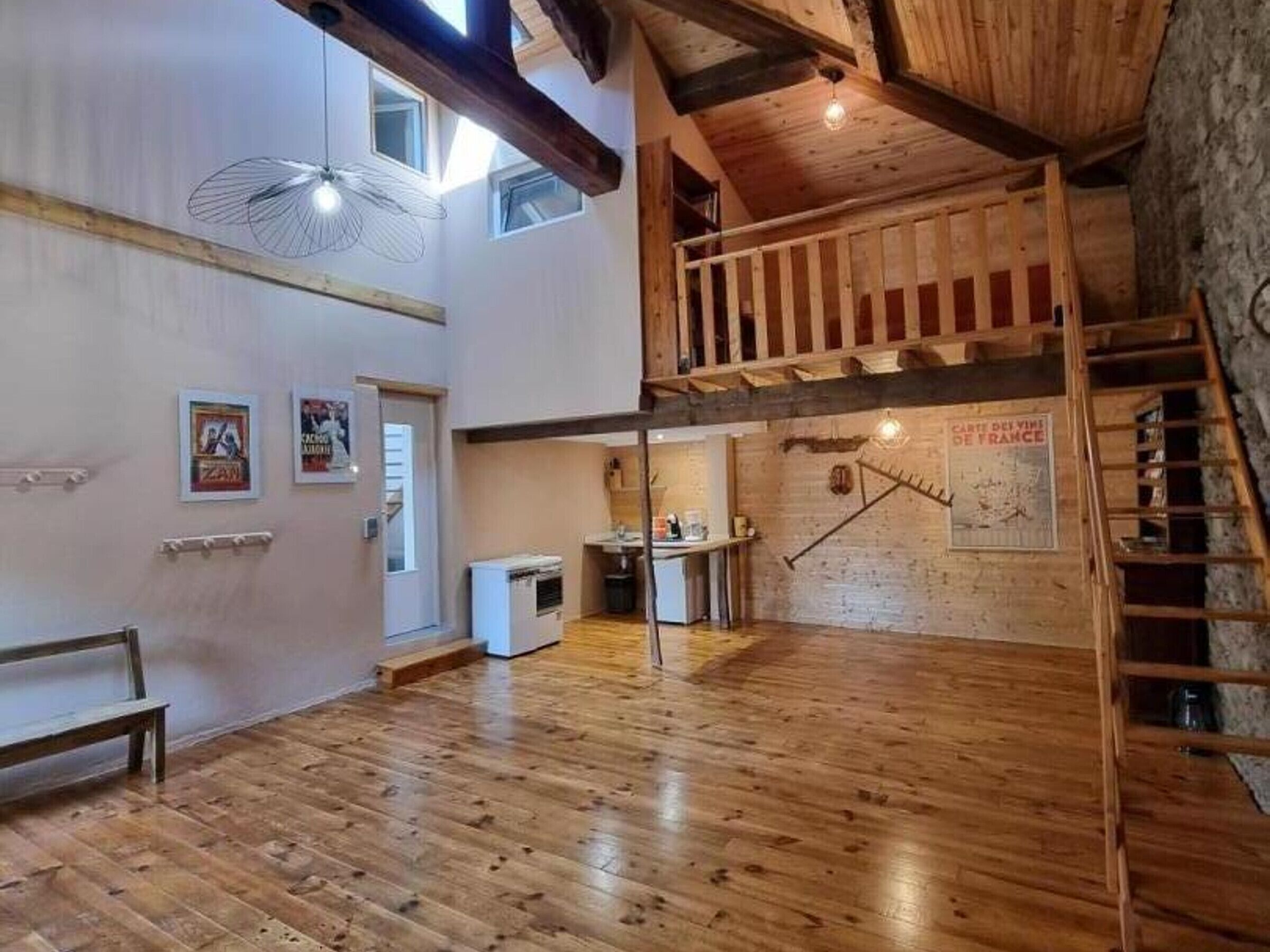 Ein geräumiges Loft mit Holzboden, Hochbett, Küchenzeile und einer Treppe.
