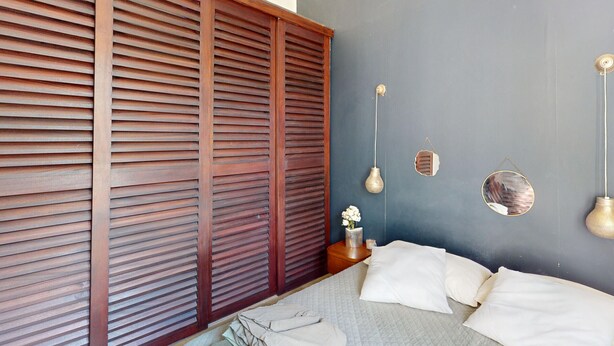 A bedroom with a bed, a wooden sliding door, a nightstand, and wall-mounted light fixtures. - House in Vic-la-Gardiole, 2 pers, Terrace, Close to Beach (Vic-la-Gardiole)