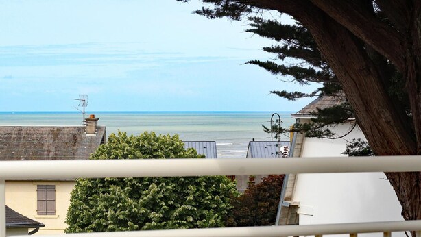 A balcony with a view of the sea, a tree, and a building in the background. - House in St Pair-sur-Mer with Garden and Private Parking, Near the Beach (Saint-Pair-sur-Mer)