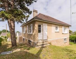A two-story house with a tiled roof, white shutters, and a stone foundation.