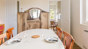 A dining area with a round table, chairs, and a cabinet with a mirror. - House in St Pair-sur-Mer with Garden and Private Parking, Near the Beach (Saint-Pair-sur-Mer)