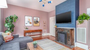 A living room with a sofa, coffee table, fireplace, TV, and artwork on the wall.