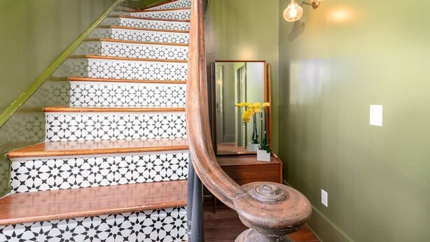 A staircase with patterned steps and a wooden handrail.