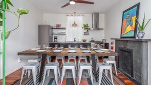 A modern kitchen with a dining table set for six, a ceiling fan, and a fireplace.
