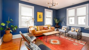 A living room with a blue wall, a sofa, armchairs, a coffee table, and a rug.