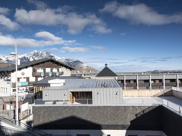A hotel with a mountain backdrop, featuring a ski lift, a restaurant, and a bar.