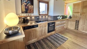 Une cuisine moderne avec des meubles en bois, un four encastré, un lave-vaisselle et une grande fenêtre.