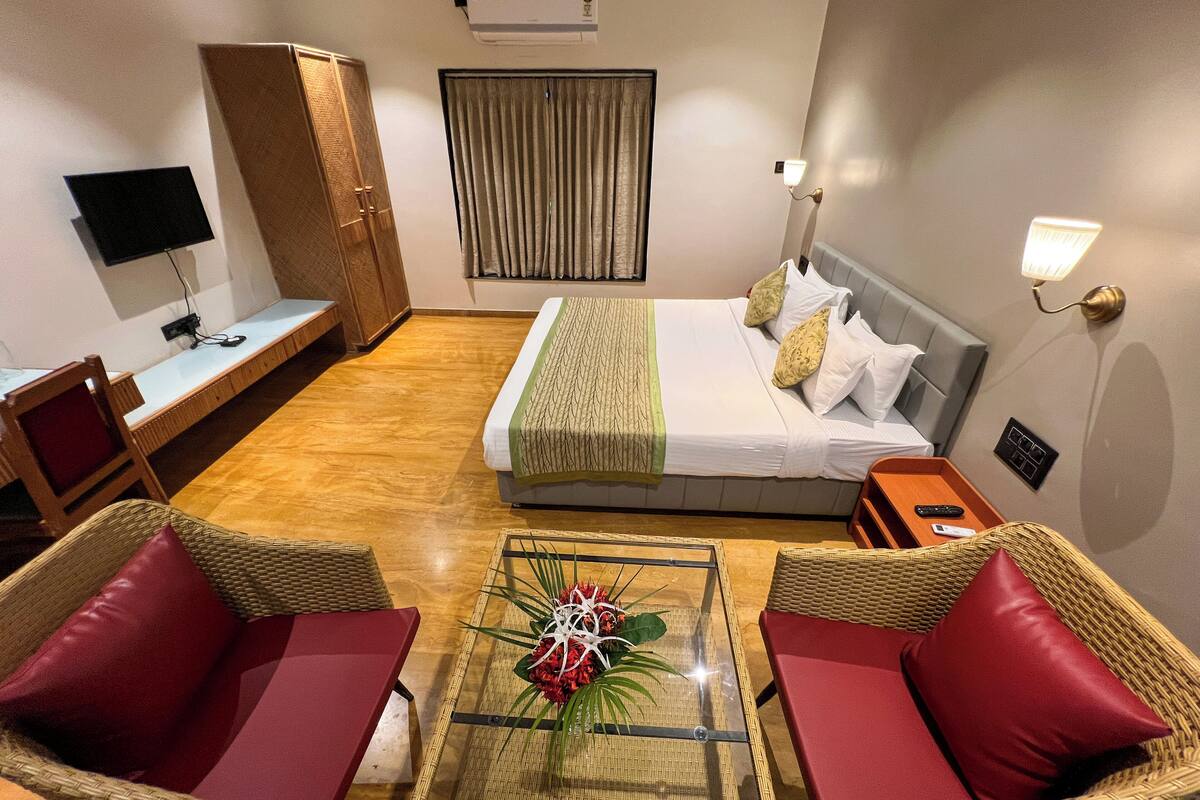 A hotel room with a bed, a desk, a chair, a table, and a television.