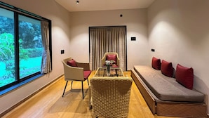 Uma sala de estar moderna com um sofá, duas poltronas de vime, uma mesa de centro de vidro e um ventilador de teto.