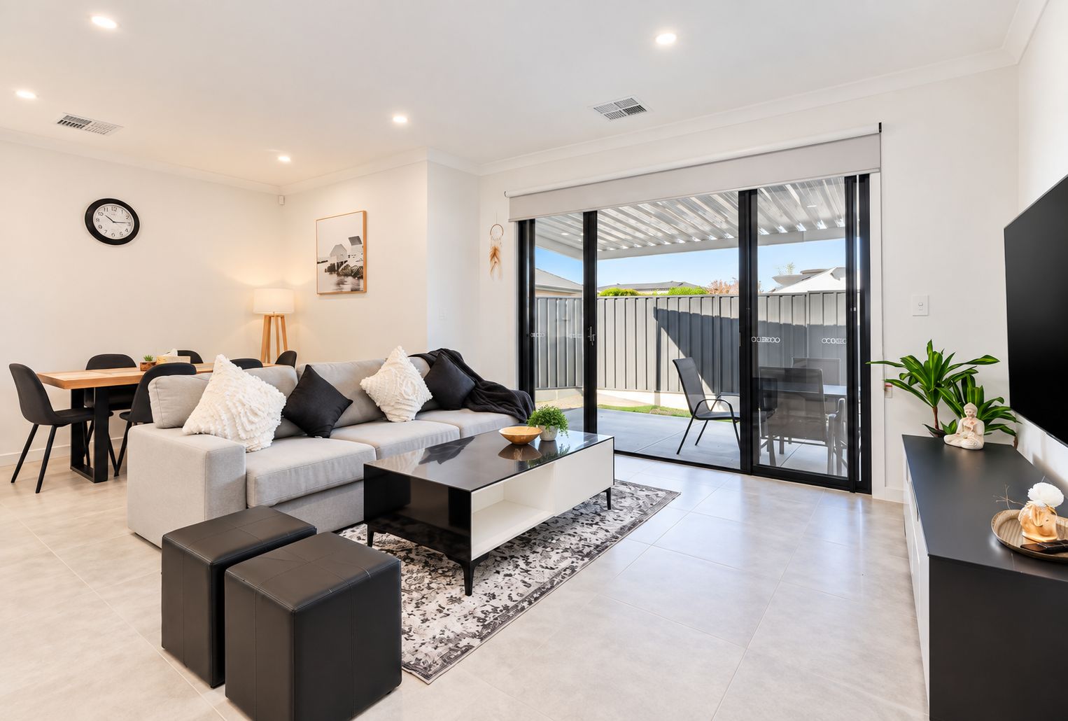 A modern living room with a sofa, coffee table, and a dining area with chairs and a table.