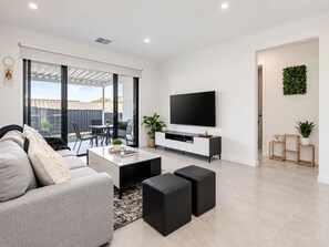 Un salon moderne avec un canapé, une table basse et des poufs noirs.