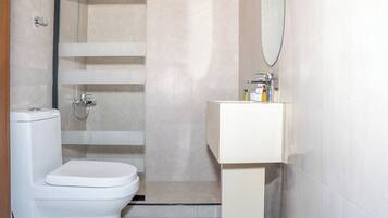 A bathroom with a toilet, a shower, and a sink.