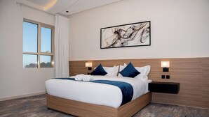 A modern hotel room with a large bed, wooden headboard, and a cityscape view through the window.