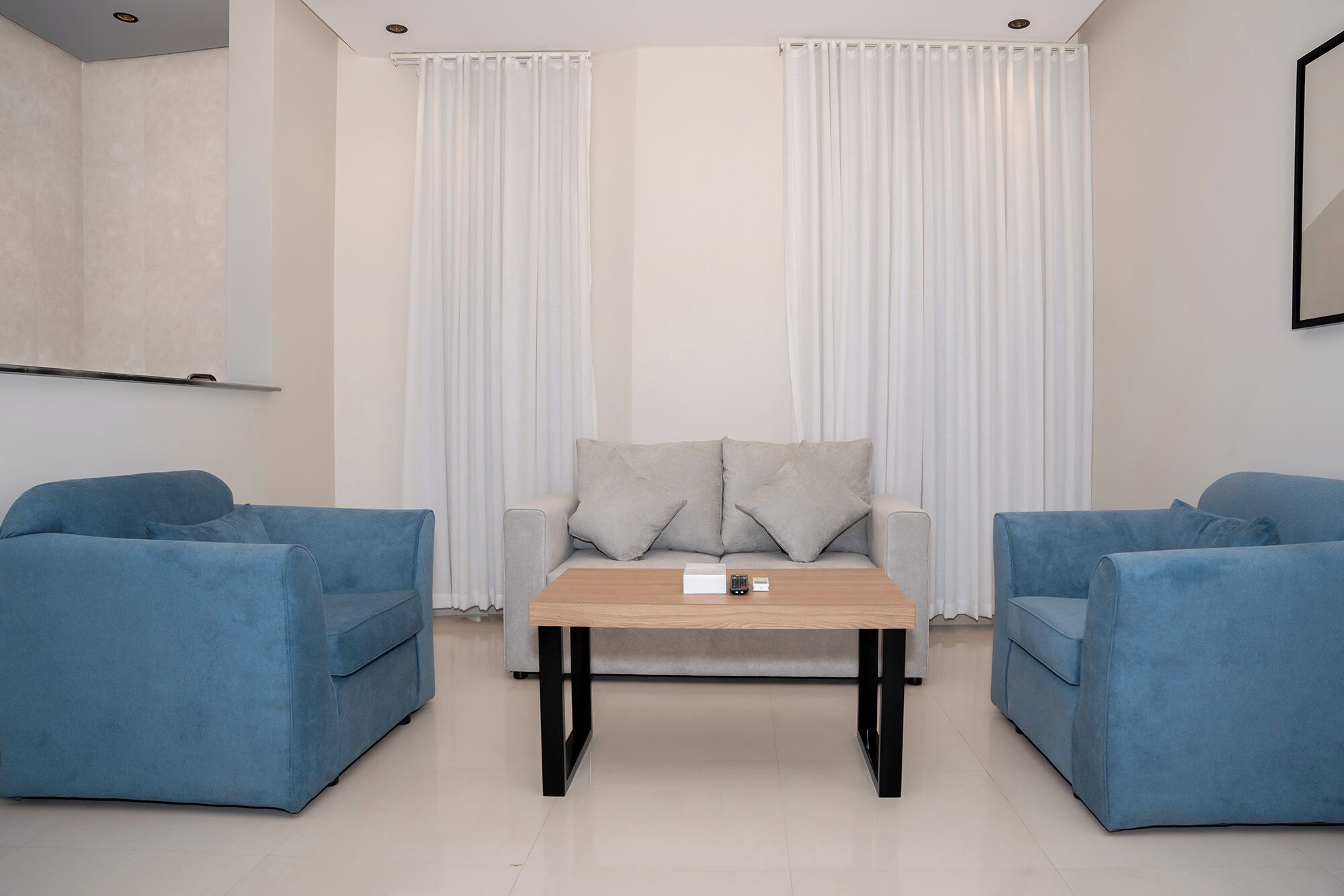 A modern living room with a sofa set, a coffee table, and a TV mounted on the wall.