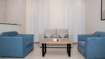 A modern living room with a sofa set, a coffee table, and a TV mounted on the wall.