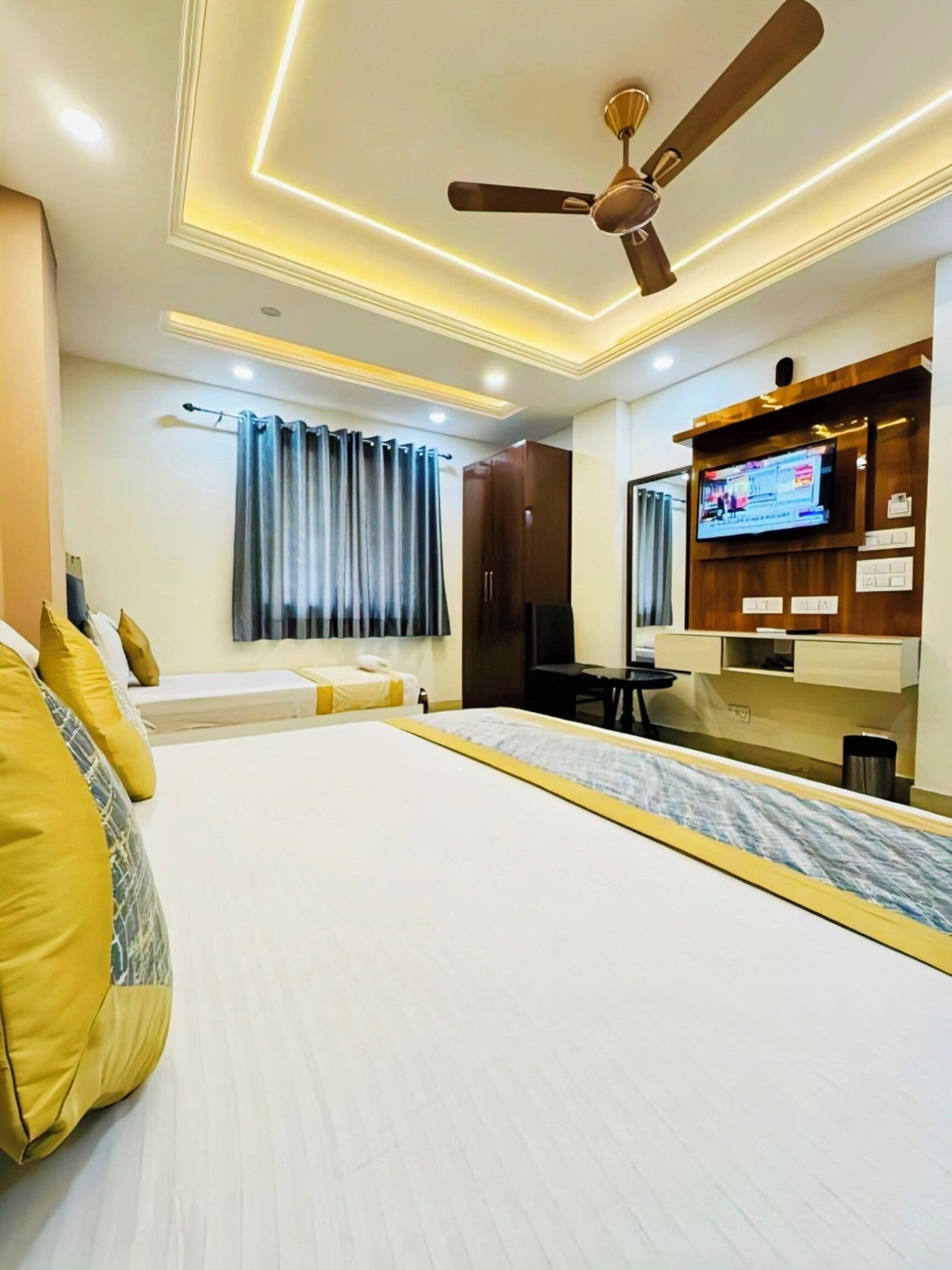 A hotel room with a bed, a desk, a television, and a ceiling fan.