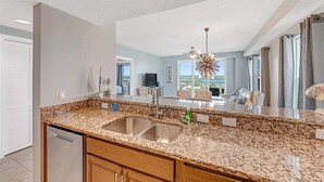 A kitchen with granite countertops, stainless steel sink, and wooden cabinets. - Southern Comfort at The Aruba (Daytona Beach)