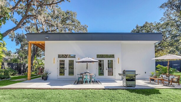 Une maison moderne dotée d’un patio, d’un barbecue et de mobilier d’extérieur.
