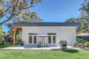 Een modern huis met een terras, een barbecue en tuinmeubilair.