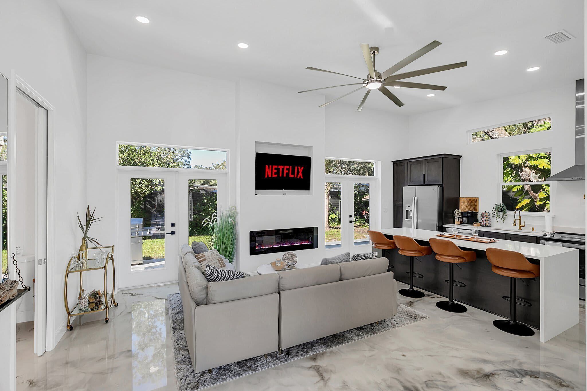 Eine moderne Küche mit einer zentralen Kochinsel, Barhocker und einem integrierten Fernseher, der 'NETFLIX' anzeigt.