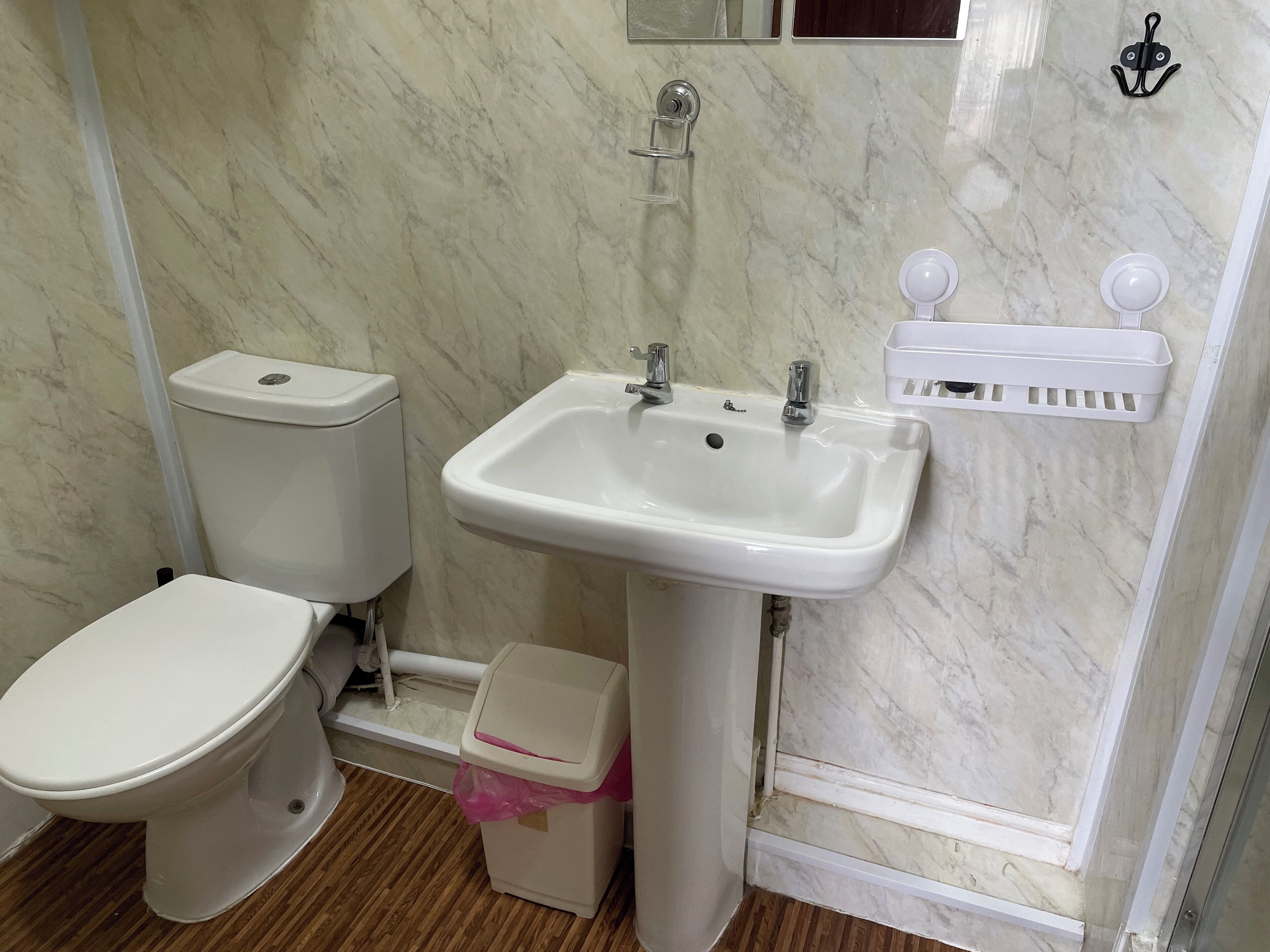 A bathroom with a toilet, sink, and a trash bin.
