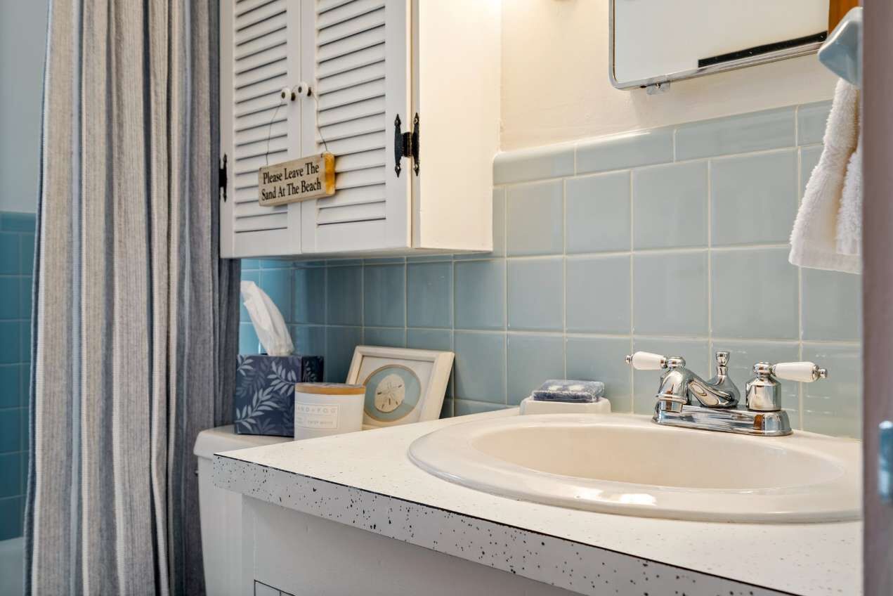 A bathroom with a sink, a towel rack, and a sign on the door.