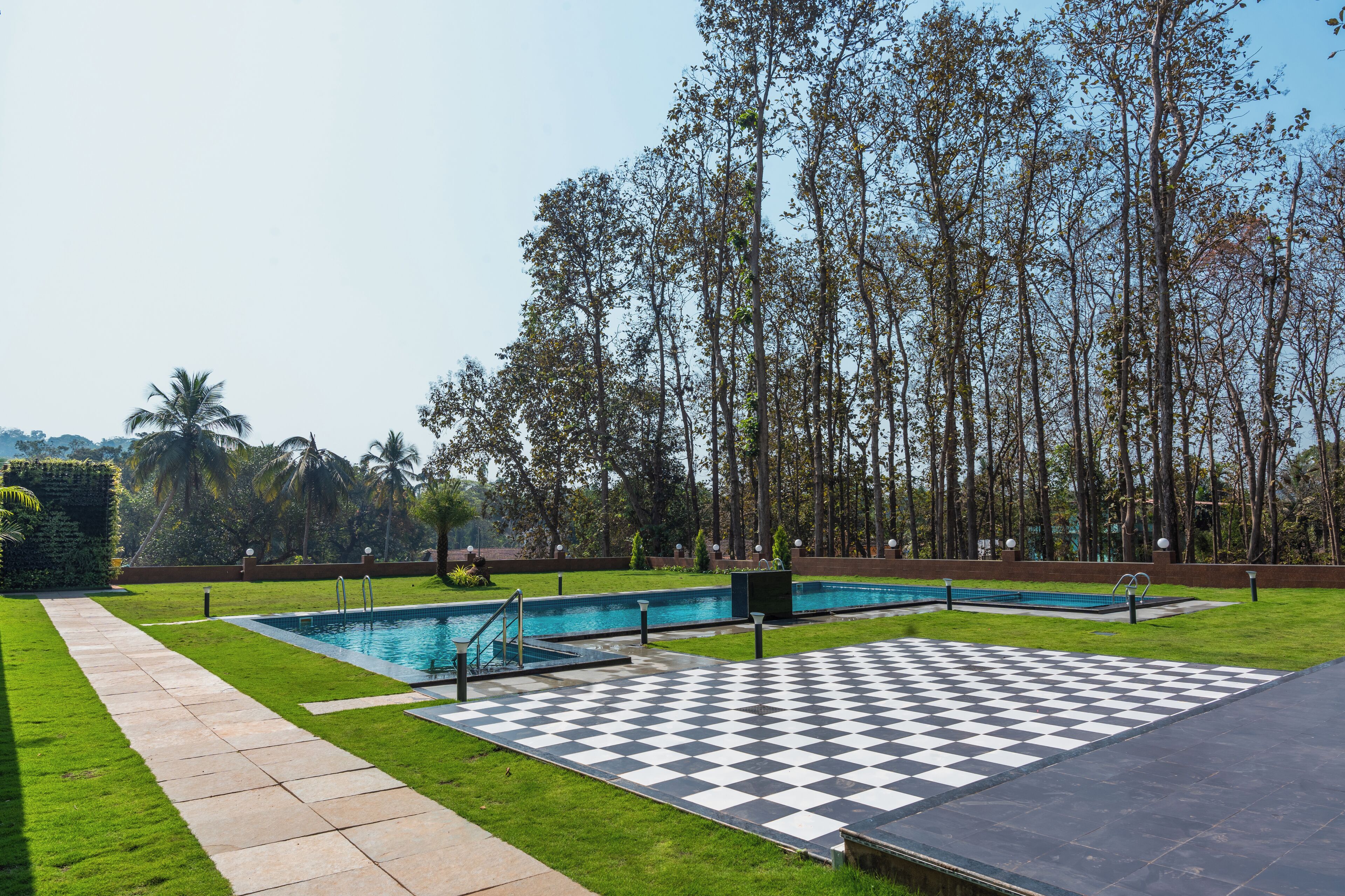 A pool area with a checkered deck, a swimming pool, and a grassy lawn.