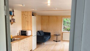 Una cocina compacta con armarios de madera, microondas y una pequeña mesa de comedor.