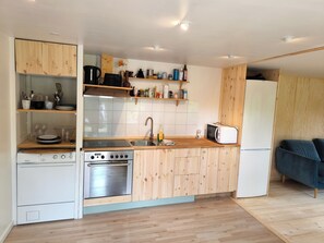 Eine kompakte Küche mit Holzausstattung, Backofen, Mikrowelle und Kühlschrank.