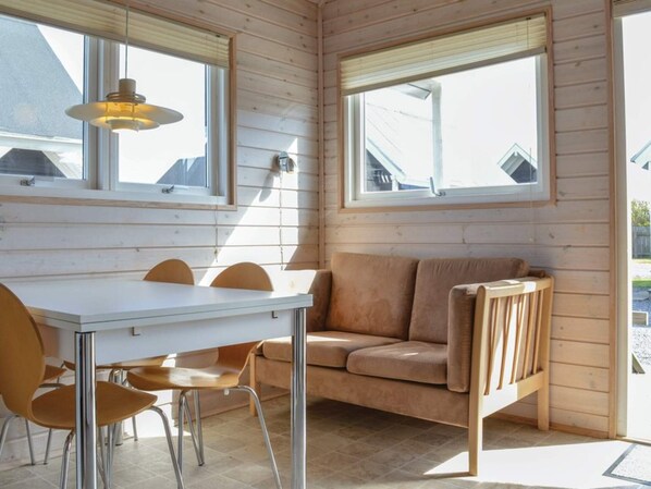 A cozy room with a white table and chairs, a beige sofa, and large windows allowing natural light. - 4 Star Holiday Home in Thyboron (Thyborøn)