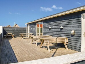 A wooden deck with picnic tables and a covered area, likely a patio or outdoor seating space. - 4 Star Holiday Home in Thyboron (Thyborøn)