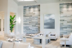 A modern living room with a marble-patterned wall, a large painting, and a potted plant.