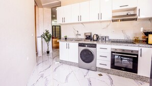 A modern kitchen with white cabinets, a built-in washing machine, and a stove. - Traditional/Modern Apartment, Full A/C, 10m to Airport, 15m to centre. (Marrakech)