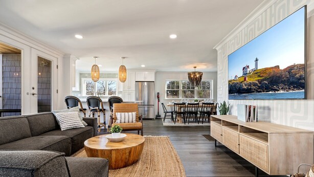 A spacious living room with a large flat-screen TV, a dining area with a wooden table and chairs, and a kitchen with modern appliances. - Game Room, Home Gym, 1 Mile to Beach (York Beach)
