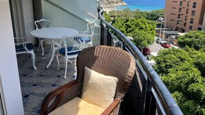 A balcony with wicker furniture, a table, and chairs.