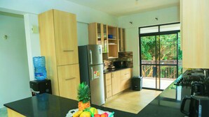 Eine moderne Küche mit Holzschränken, einem Edelstahlkühlschrank und einem großen Fenster mit Blick auf Grünflächen.