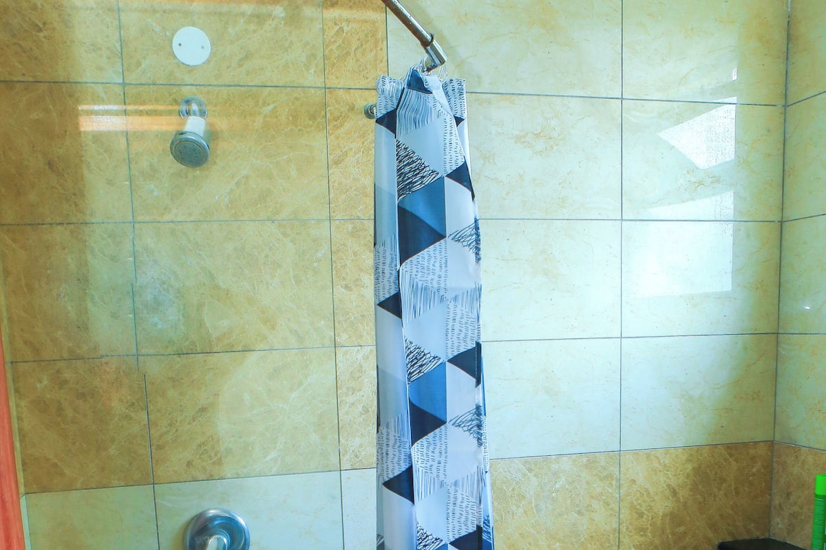 A bathroom with a shower, toilet, and a towel rack.