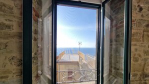 A window with a view of a balcony and the sea.