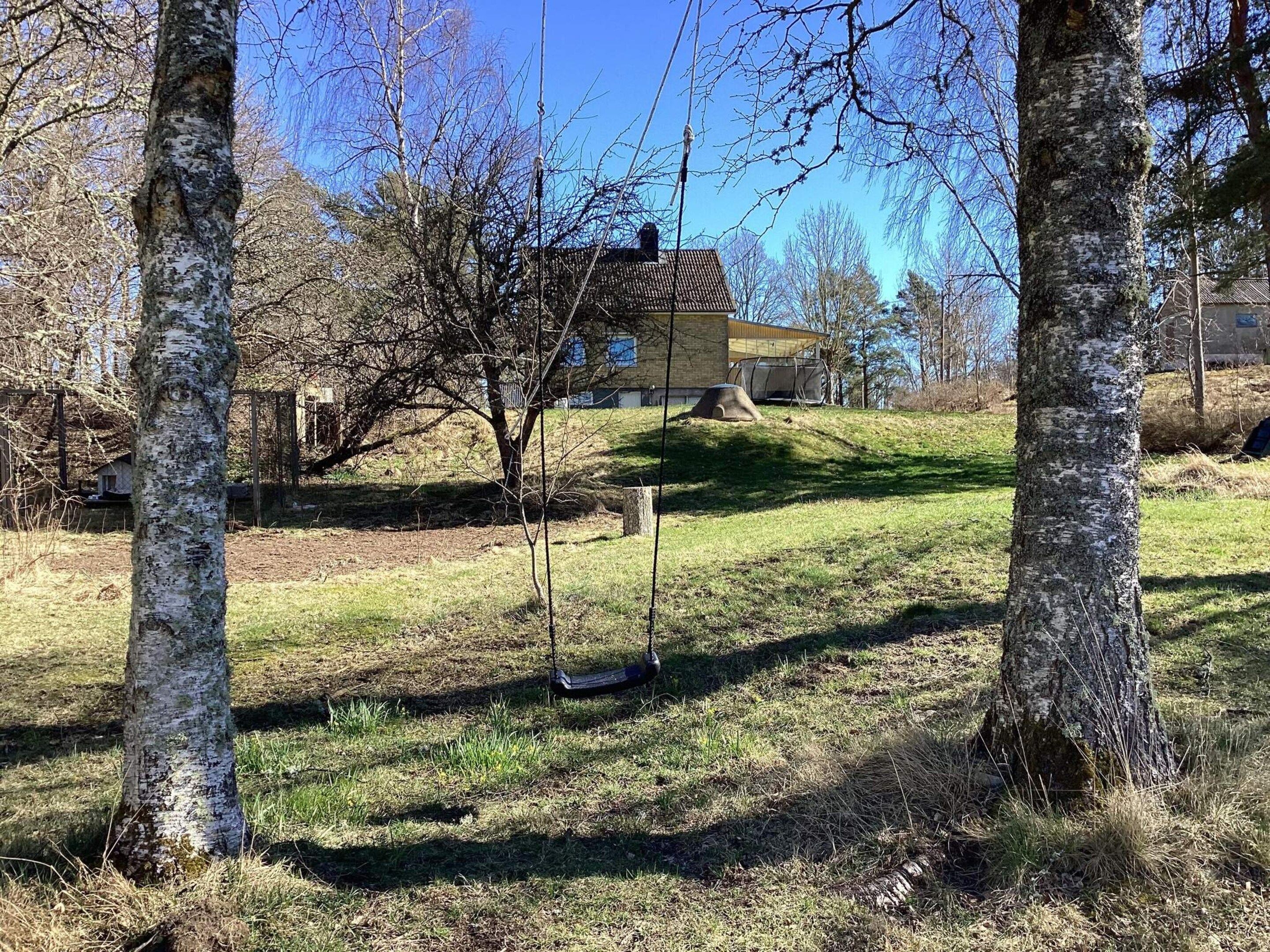 A house with a sloped roof, surrounded by trees and a grassy area.