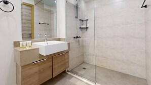 Une salle de bain moderne avec un lavabo blanc, un meuble-lavabo en bois et une cabine de douche en verre.