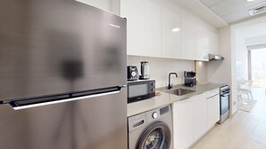 Une cuisine moderne équipée d’un réfrigérateur en acier inoxydable, d’un four à micro-ondes encastré, d’un lave-linge et d’un évier.