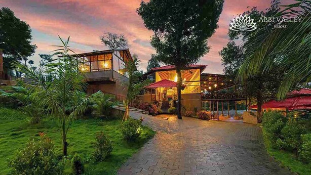 A resort with a paved pathway leading to a building with a red roof and glass windows. - Abbi Valley Resorts  (Sakleshpur)