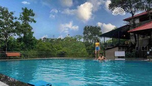 A swimming pool with a person standing in the water, another person in the background, and a bench along the poolside. - Abbi Valley Resorts  (Sakleshpur)